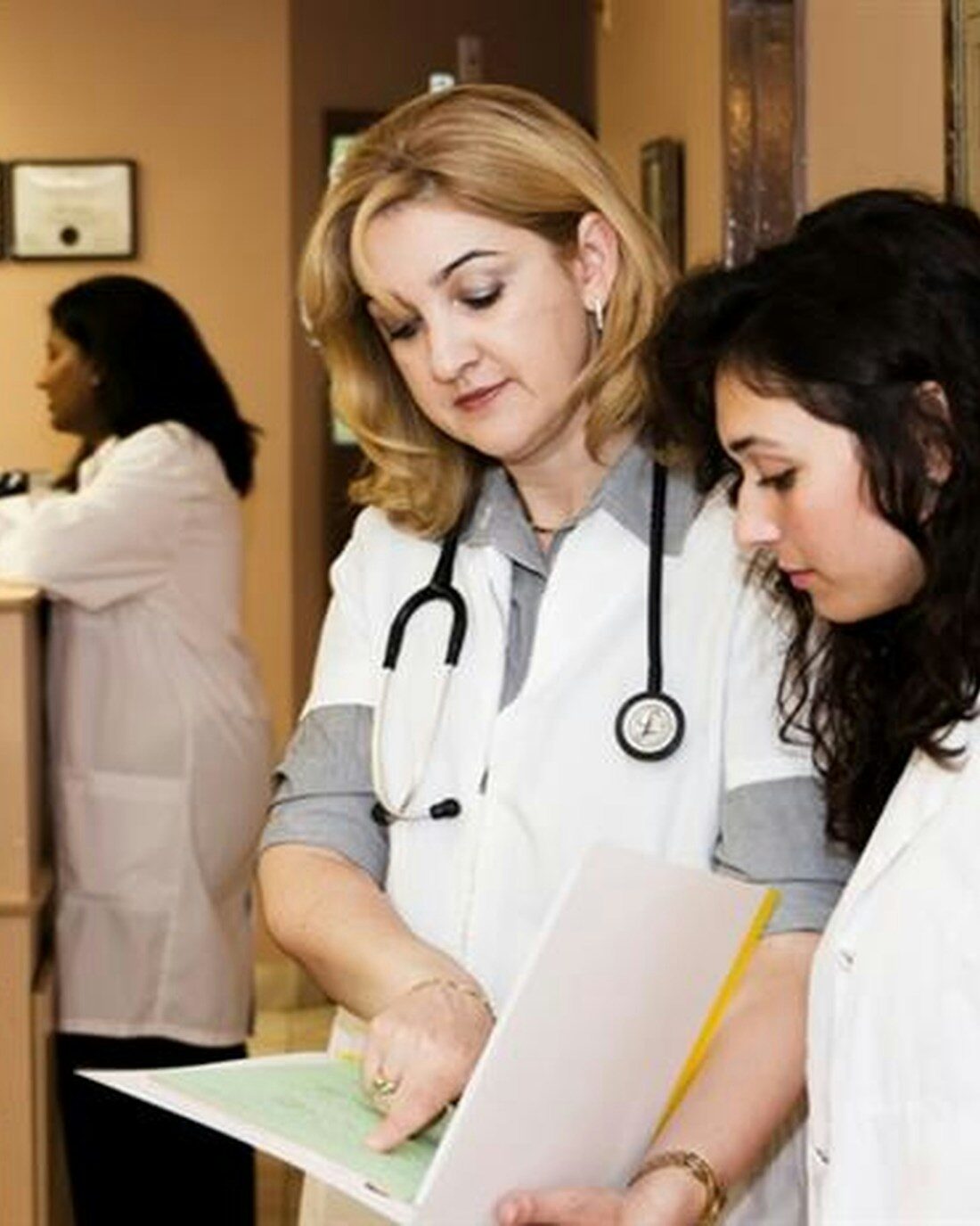 Medical front-desk staff reviewing insurance paperwork on a laptop