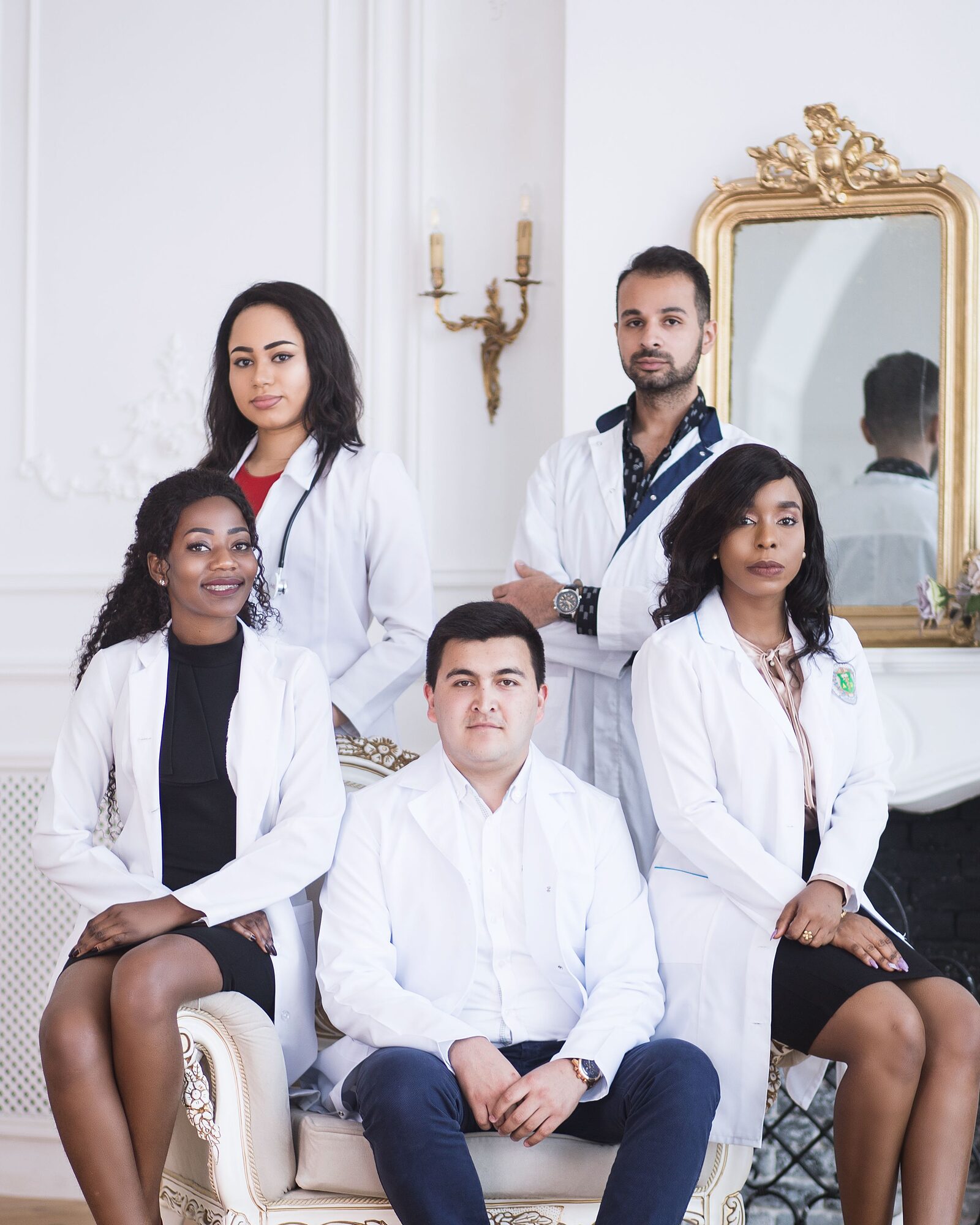A team of five medical professionals in white coats